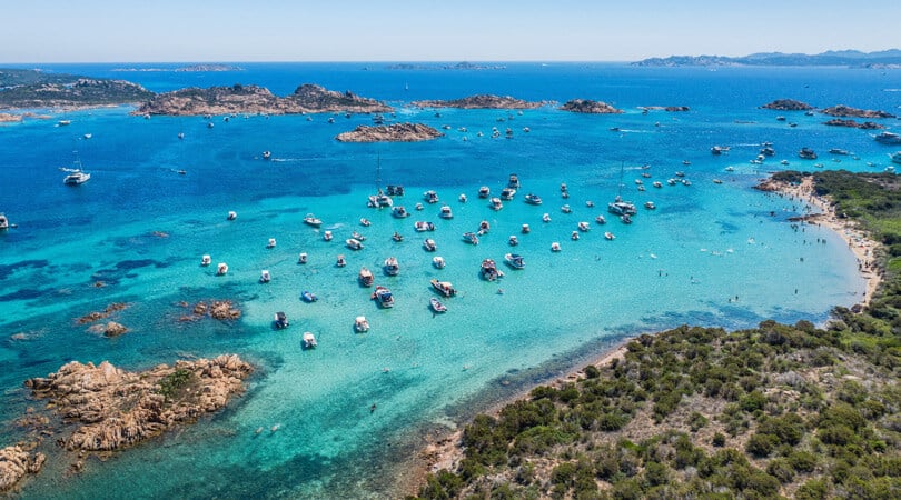 Boats in water next to coast of Sardinia